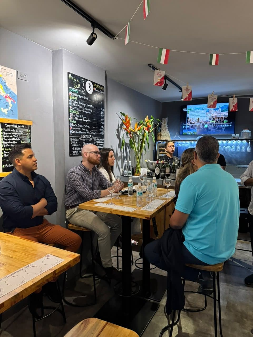 Invitados atentos en la cata «Contrastes de Italia», con la pizarra de vinos al fondo